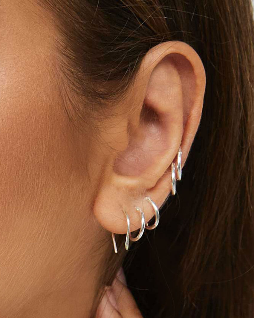 Model wears silver Arc Earrings and Mini Hoops in multiple piercings